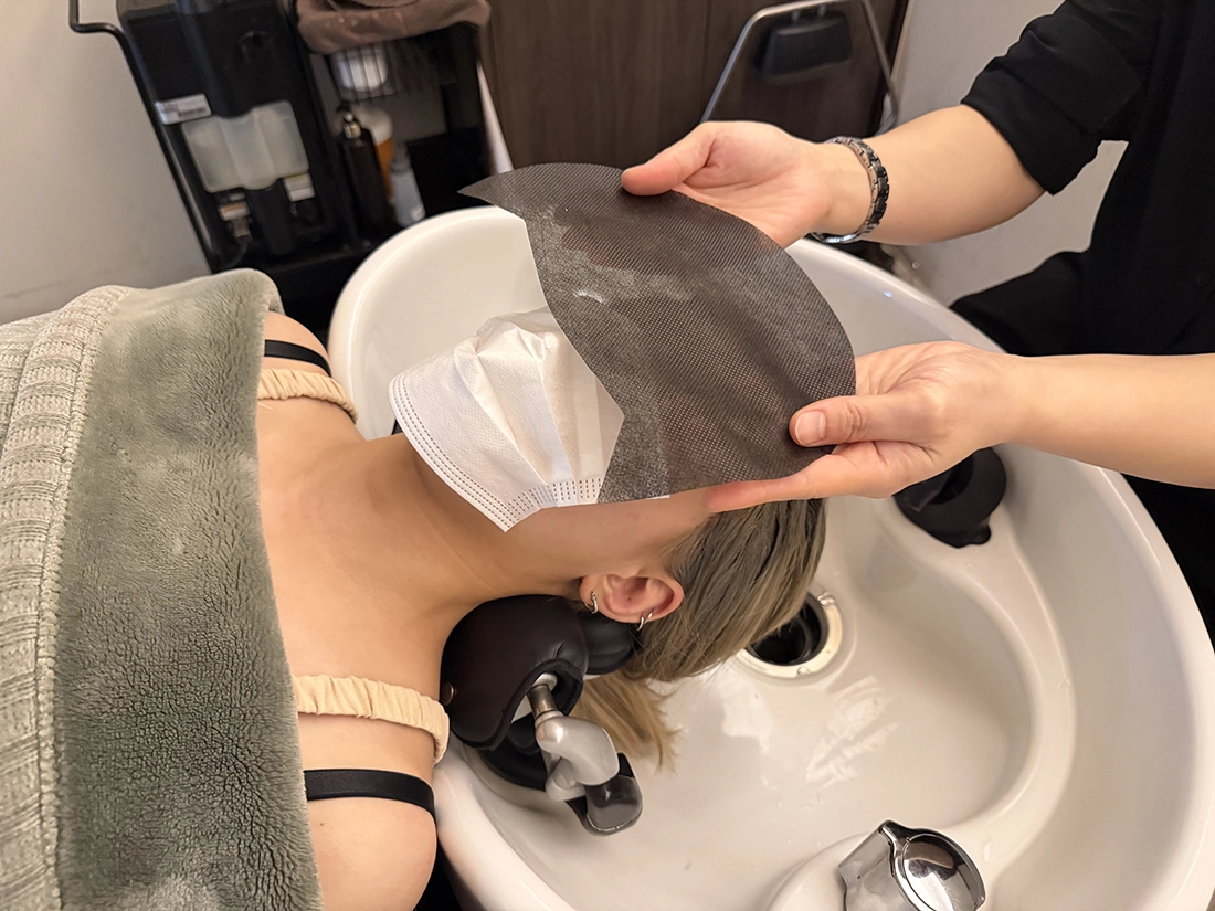 Customer covering their face for a more comfortable shampoo experience